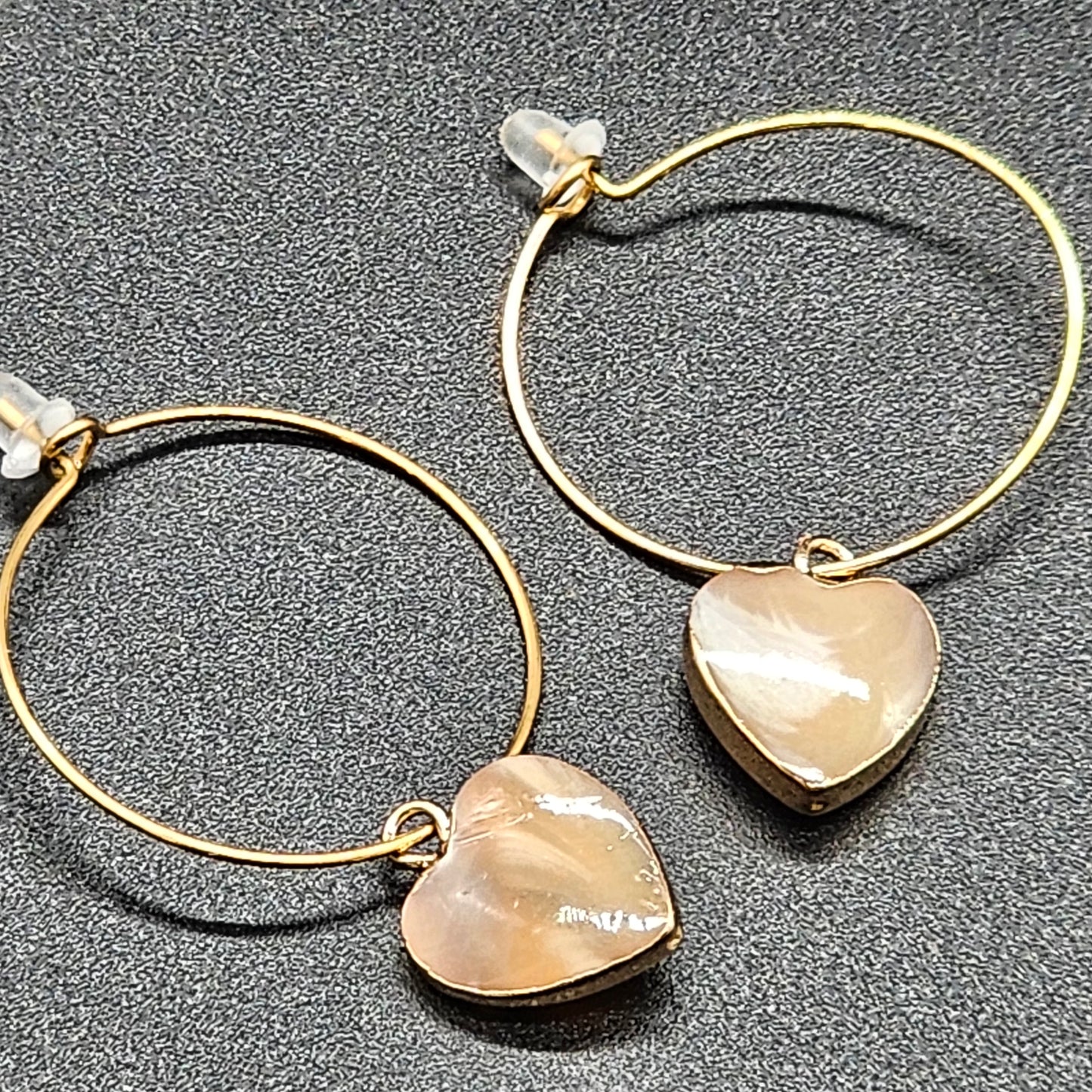 Gold hoop earrings with a mother-of-pearl heart charm, hypoallergenic stainless steel.