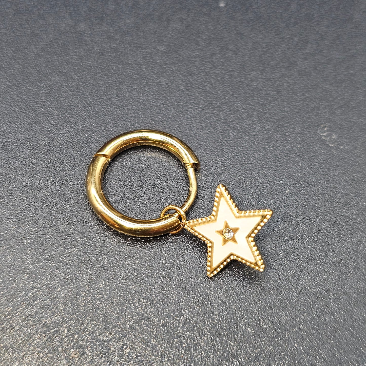 Boucle d’oreille dorée en forme d’étoile bordée de nacre et ornée d’un strass