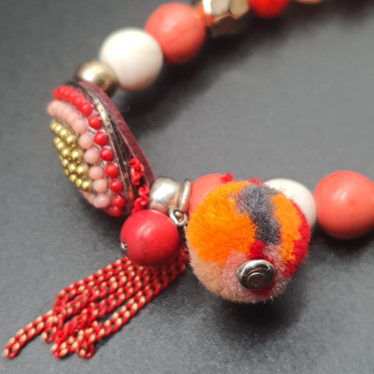 Bracelet élastique perles rouges dorées pompon tassel