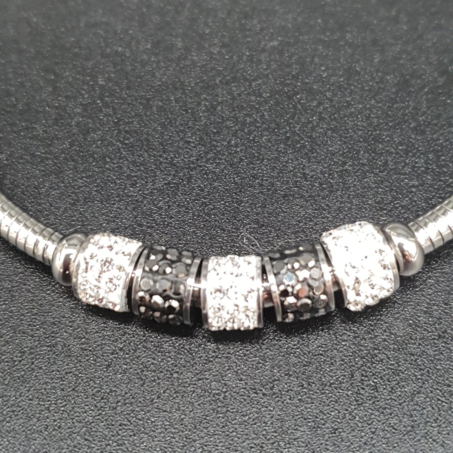 Bracelet aimanté maille oméga argentée tubes métal strass blancs éclats de cristal noirs