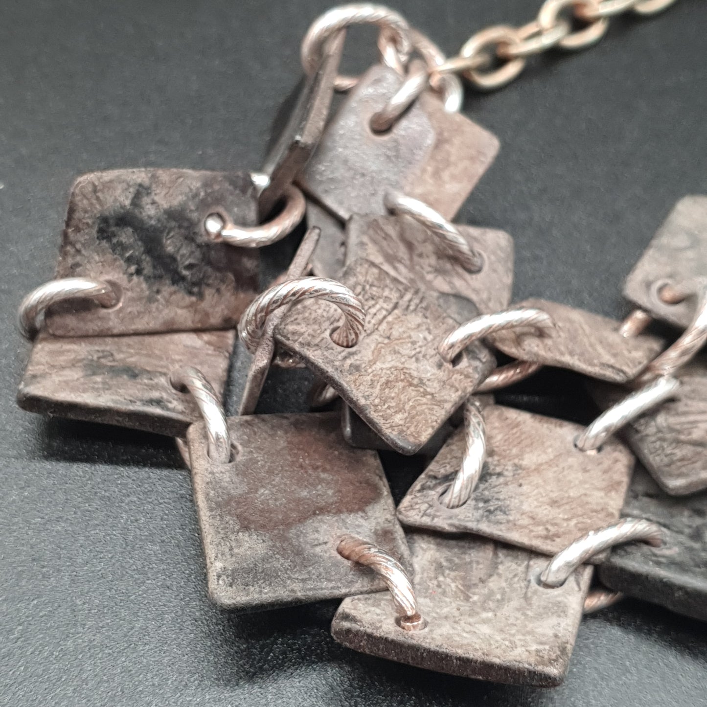 Triple-strand aged steel necklace with chunky links and geometric hammered lozenges