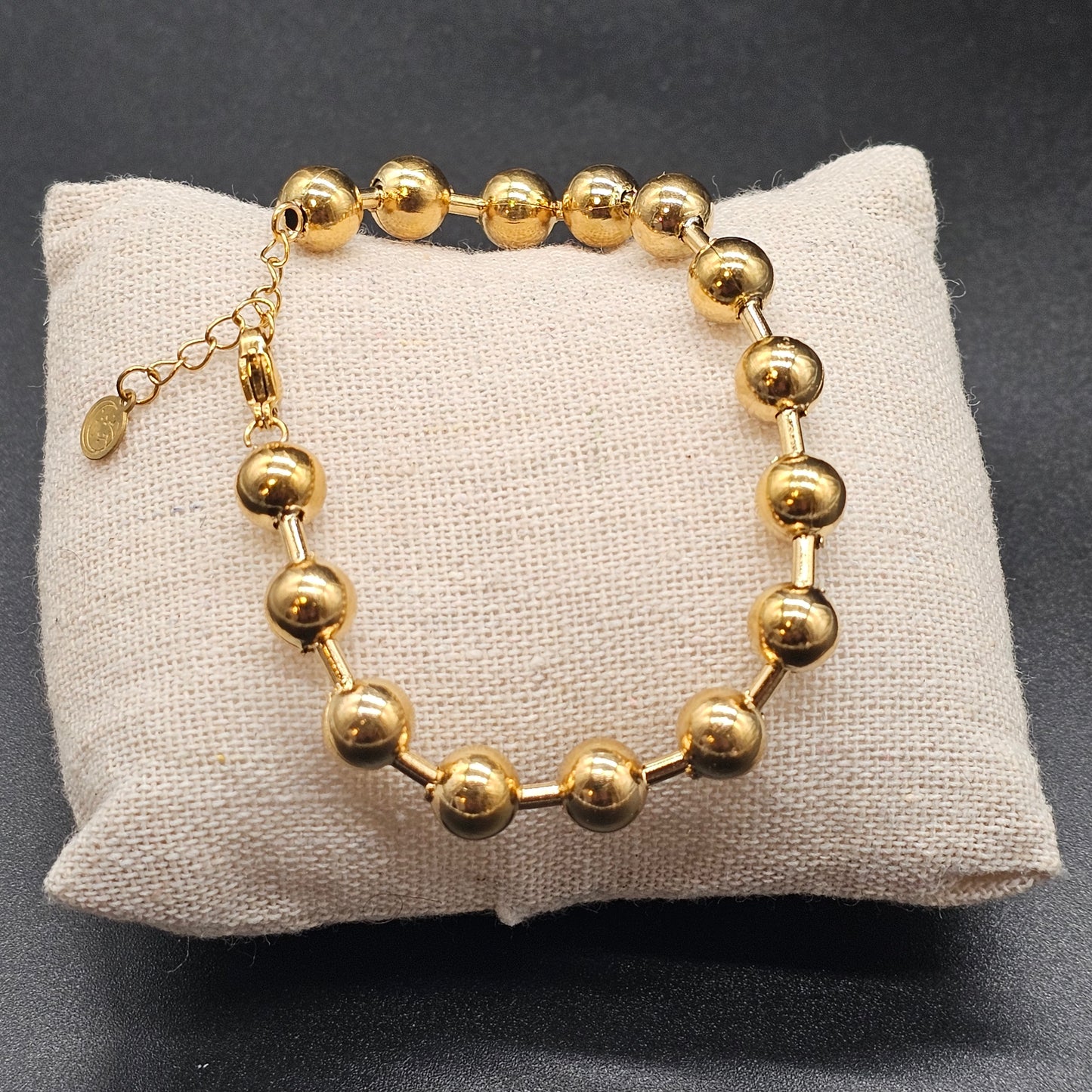 Détail du bracelet doré composé de boules en acier inoxydable brillant, style moderne et raffiné