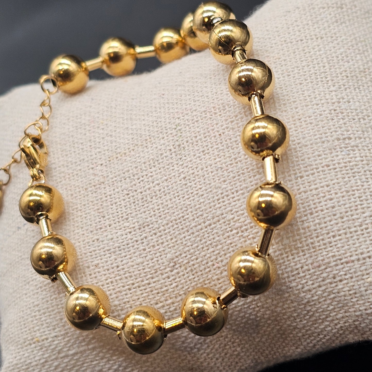Gros plan sur le bracelet boules dorées, bijou tendance pour femme en acier inoxydable.
