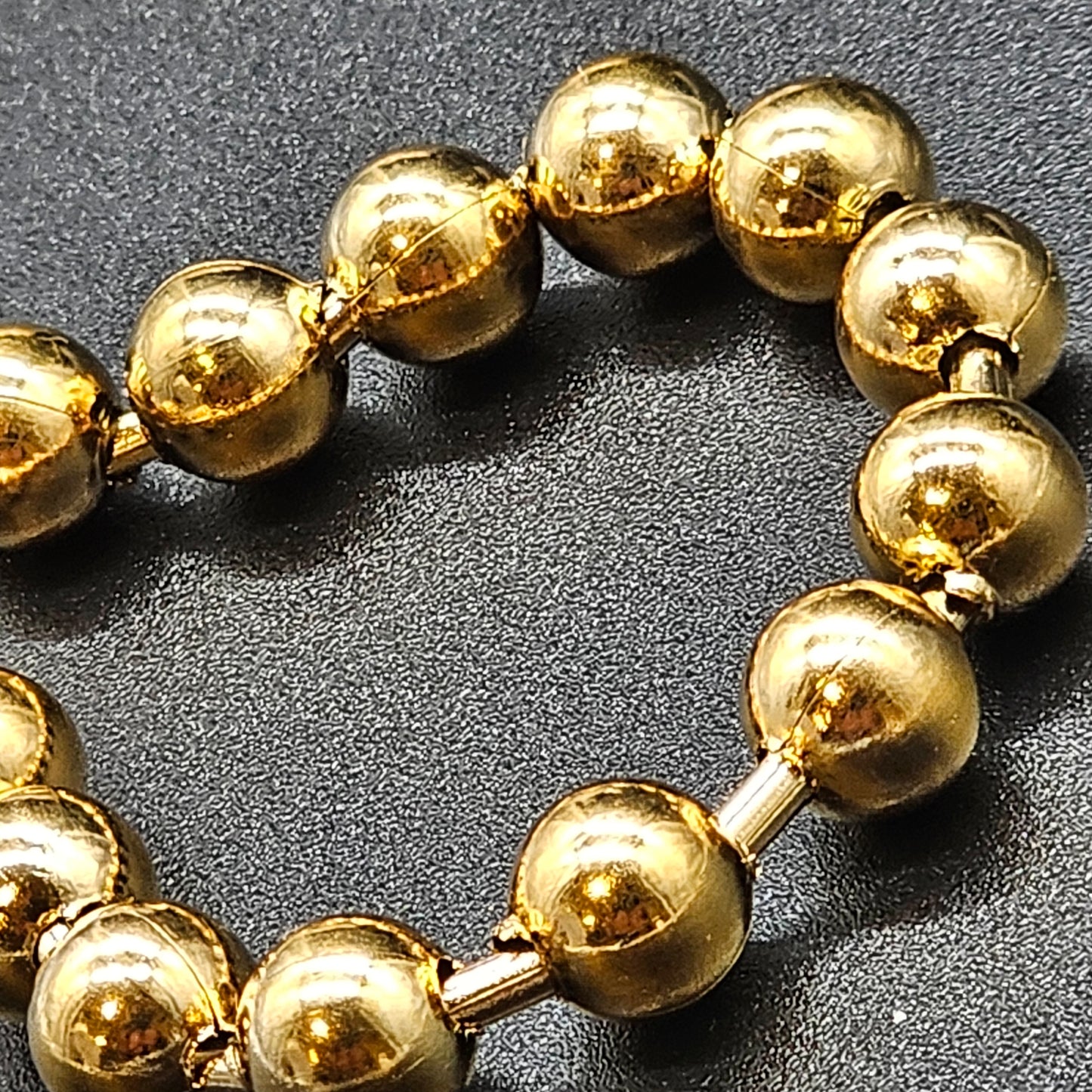 Gros plan sur le bracelet boules dorées, bijou tendance pour femme en acier inoxydable.