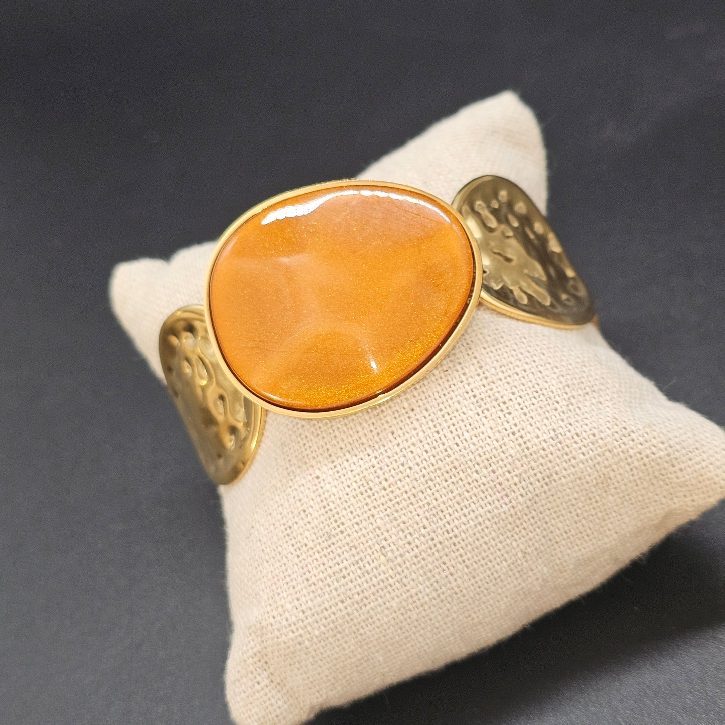 Zoom sur la pierre ocre et les bords martelés dorés de la manchette.