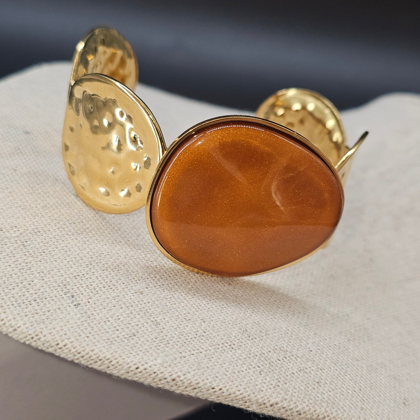 Vue latérale de la manchette dorée à pierre ocre, effet lumineux.