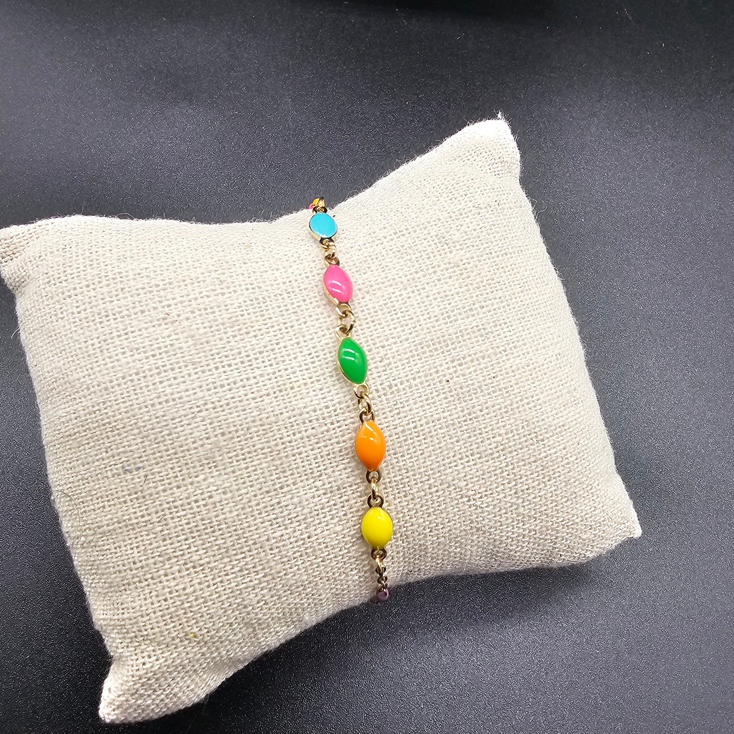 Détail du bracelet en acier doré avec perles colorées, bijou tendance pour un look estival.