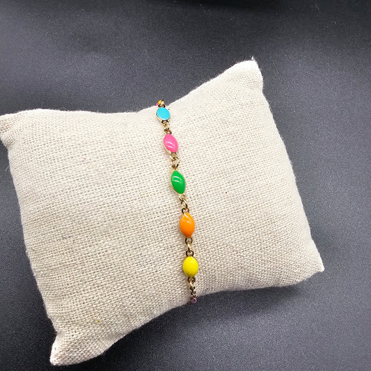 Détail du bracelet en acier doré avec perles colorées, bijou tendance pour un look estival.