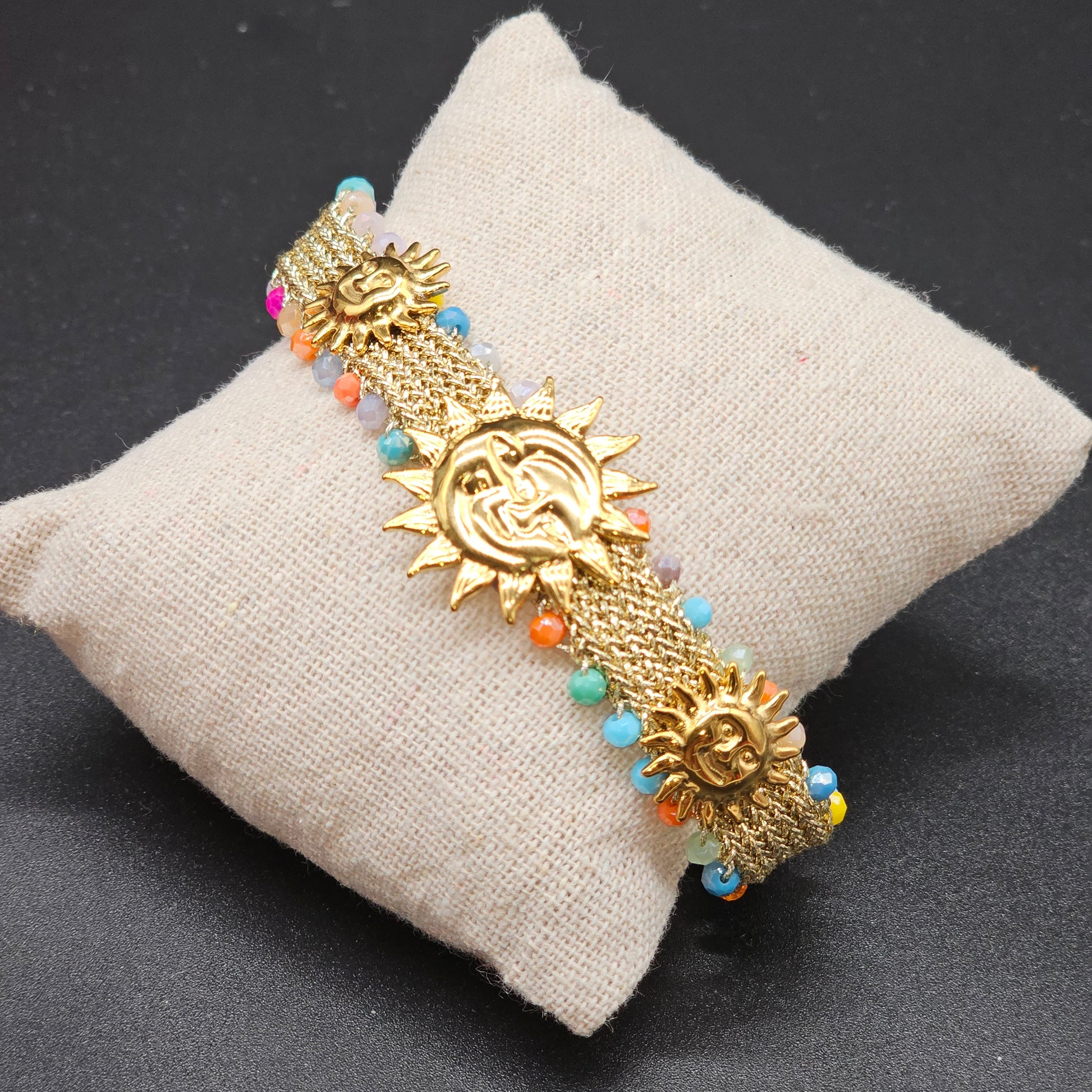 Bracelet soleil doré sur coussin beige avec perles multicolores