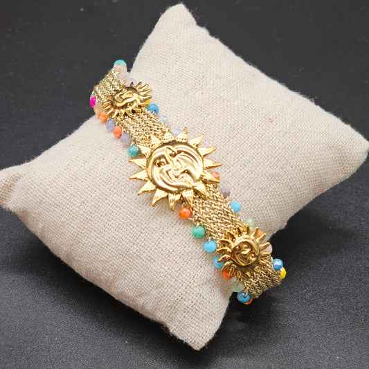 Bracelet soleil doré sur coussin beige avec perles multicolores
