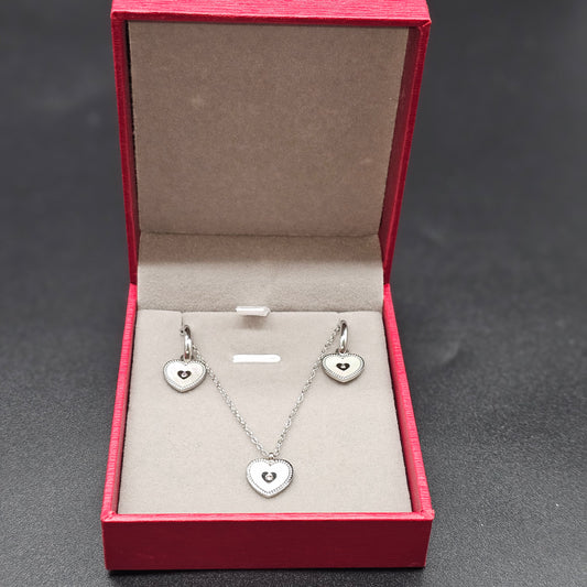 Coffret argenté complet avec collier et boucles d’oreilles cœur, présenté dans une boîte rouge élégante.