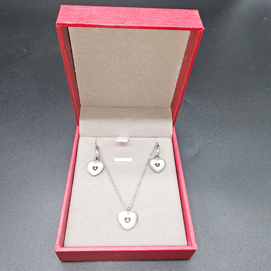 Coffret cœur argenté avec collier et boucles d’oreilles en acier inoxydable dans une boîte rouge ouverte.