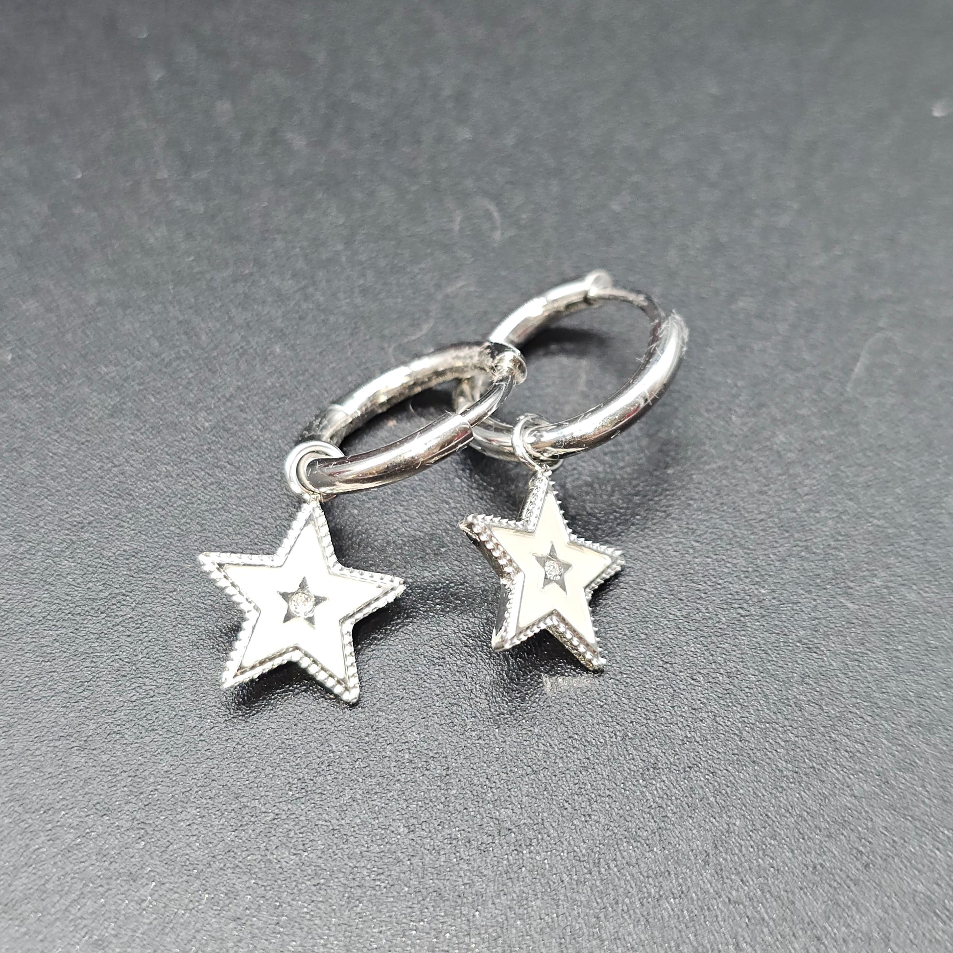 Paire de boucles d’oreilles argentées avec pendentif étoile et strass central.