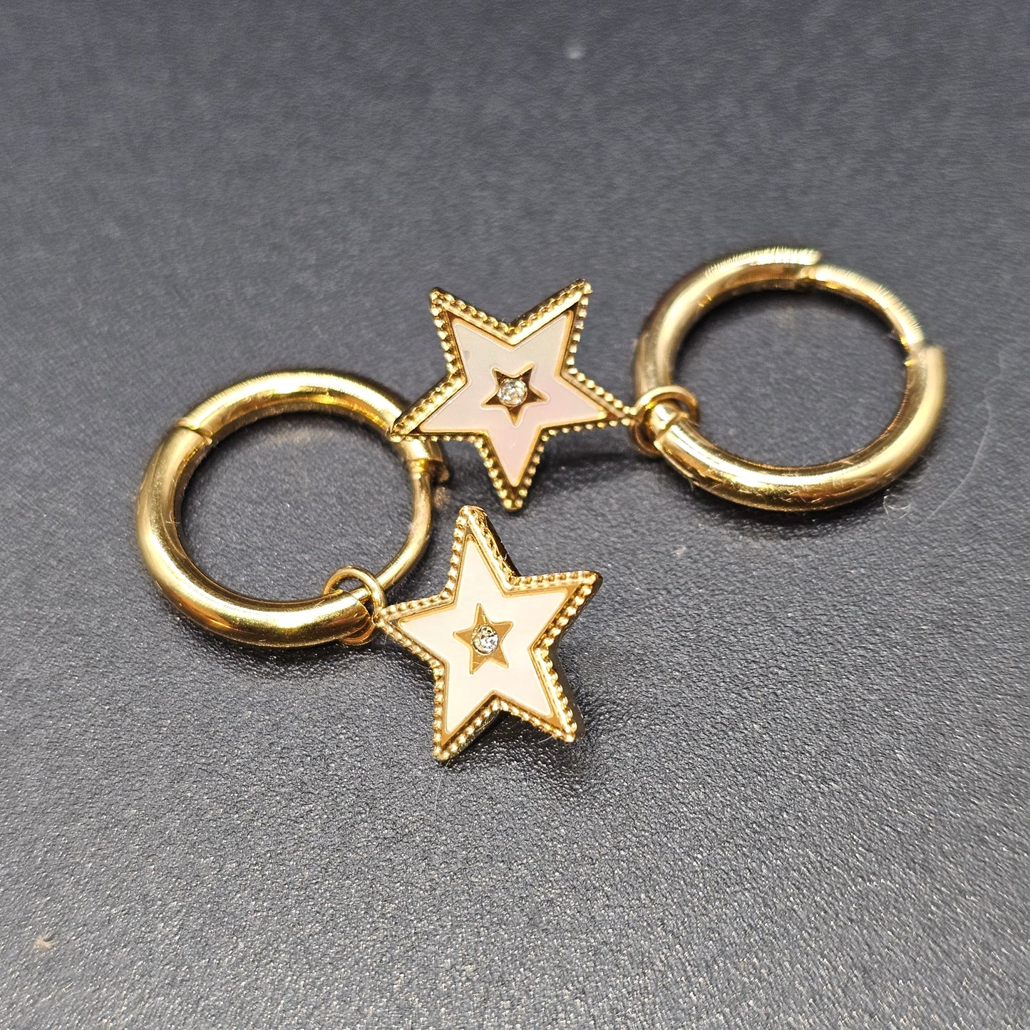 Paire de boucles d’oreilles dorées avec pendentif étoile et strass central.