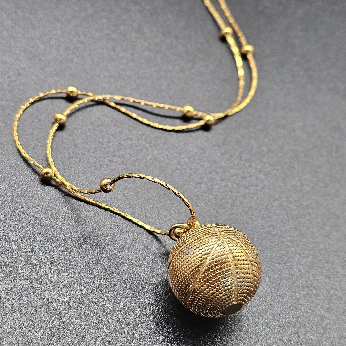 Détail du collier doré en acier inoxydable avec pendentif forme balle de basket, finition élégante et moderne.
