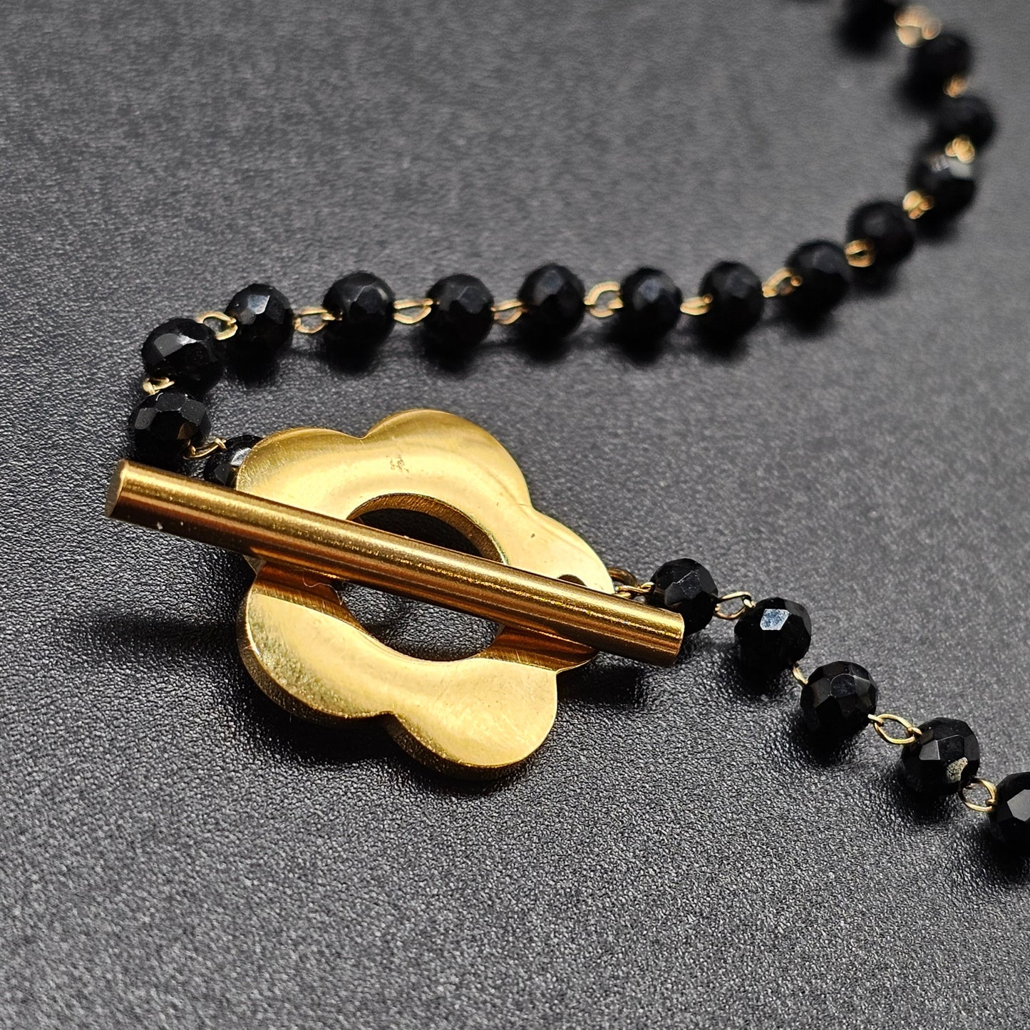 Gold stainless steel necklace with thin chain, black faceted beads and gold flower T-bar clasp