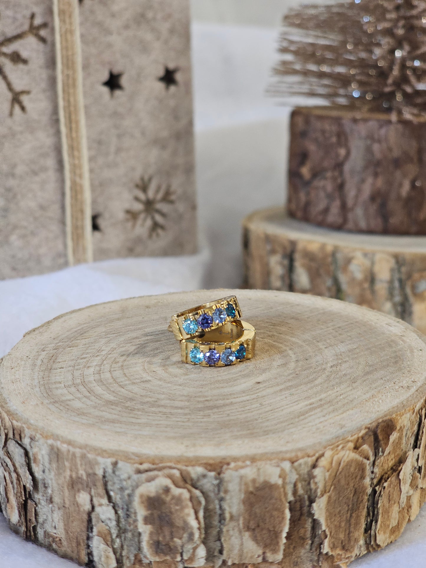 créoles dorées strass bleus scintillants sur support bois