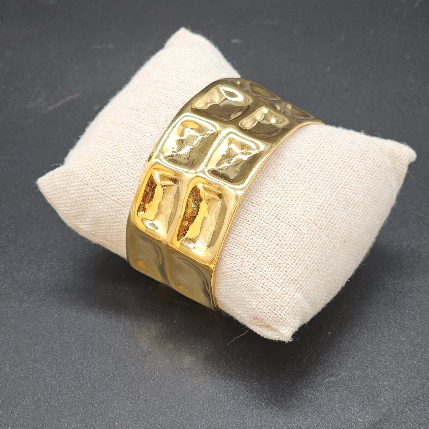 Bracelet manchette cubique doré en acier inoxydable brillant sur coussin beige – Bijoux Nic