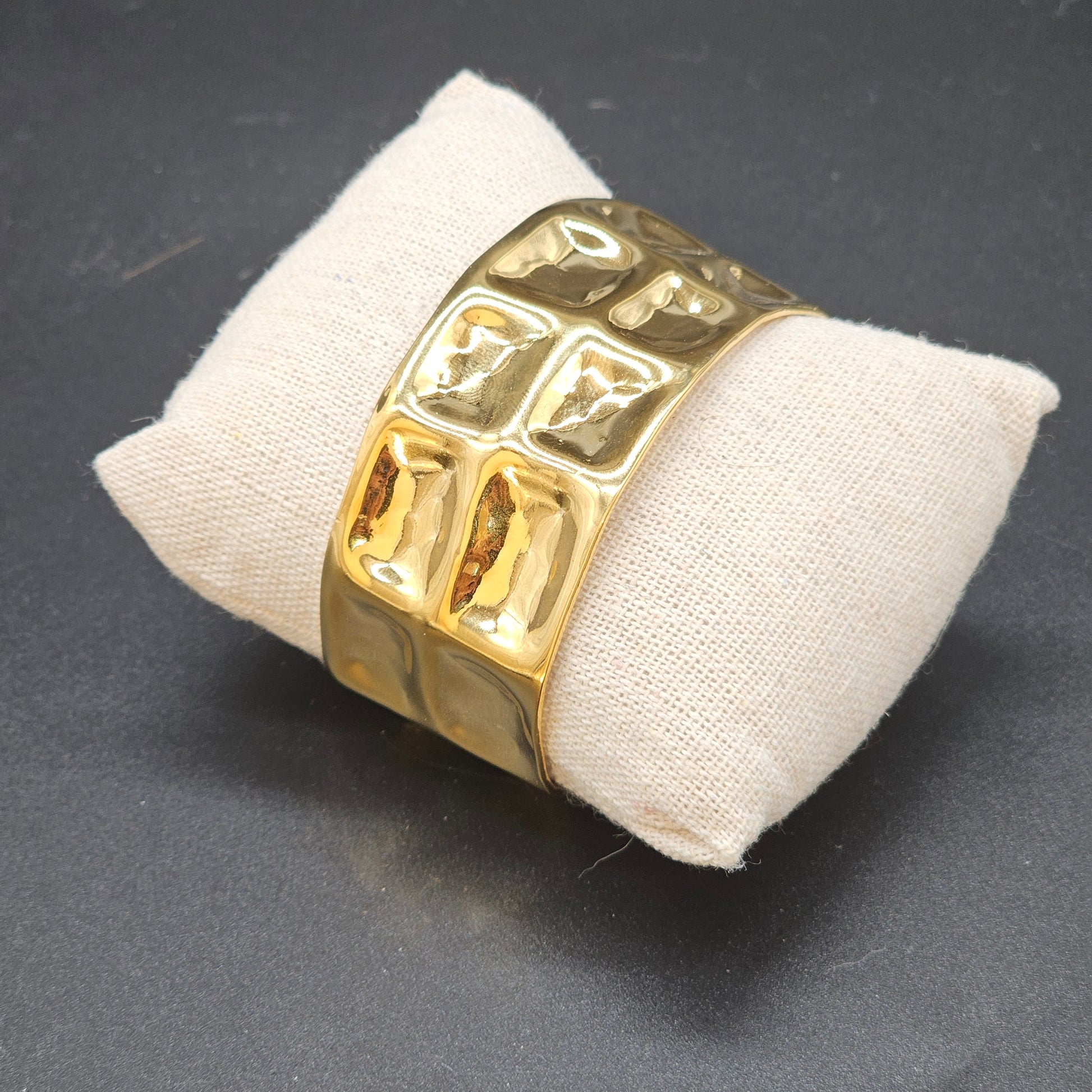 Bracelet manchette cubique doré en acier inoxydable brillant sur coussin beige – Bijoux Nic