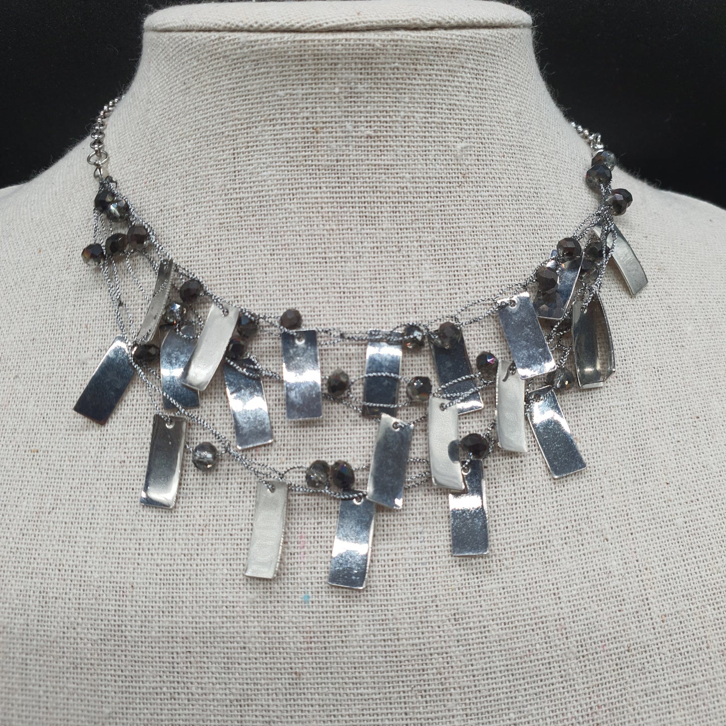 Triple strand silver-plated necklace with delicate chains, faceted beads, and metallic pieces
