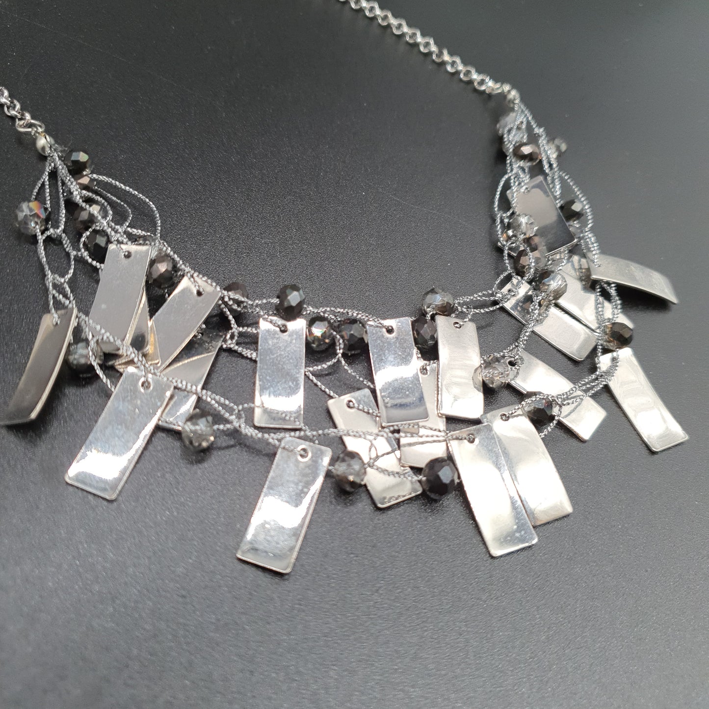 Triple strand silver-plated necklace with delicate chains, faceted beads, and metallic pieces