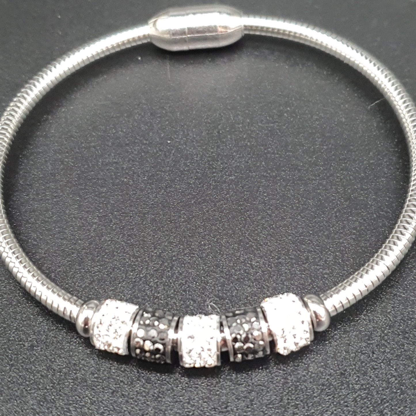 Silver-plated omega mesh magnetic bracelet with metal tubes, white rhinestones, and black crystal shards