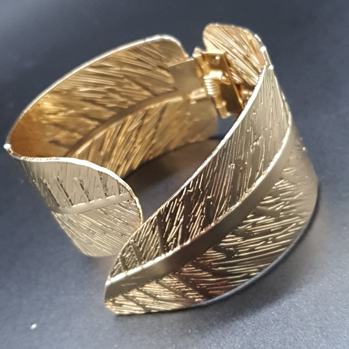 Gold-plated openwork hinged cuff bracelet with intertwined feathers